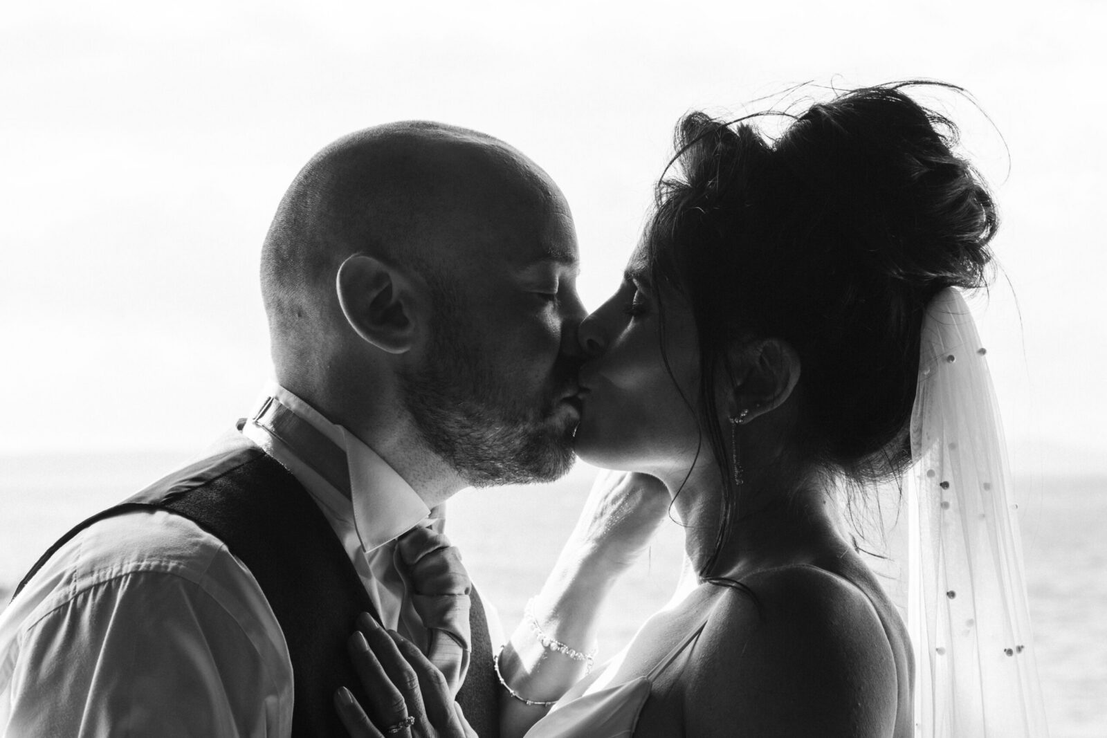 Scottish bride and groom kissing black and white backlit